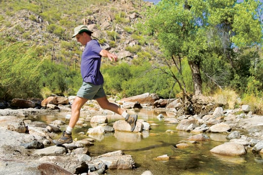 Man hiking on rocks over a stream