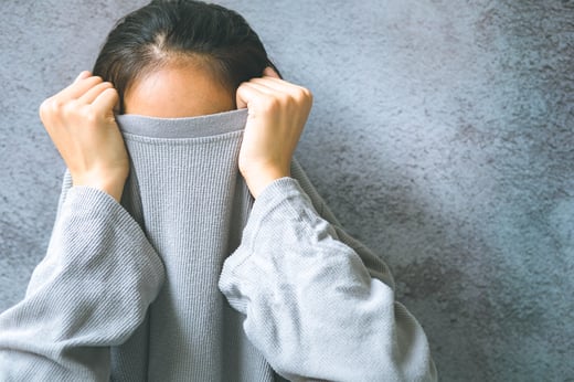 Embarrassed woman pulling shirt over face