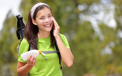 Young woman putting on sunscreen